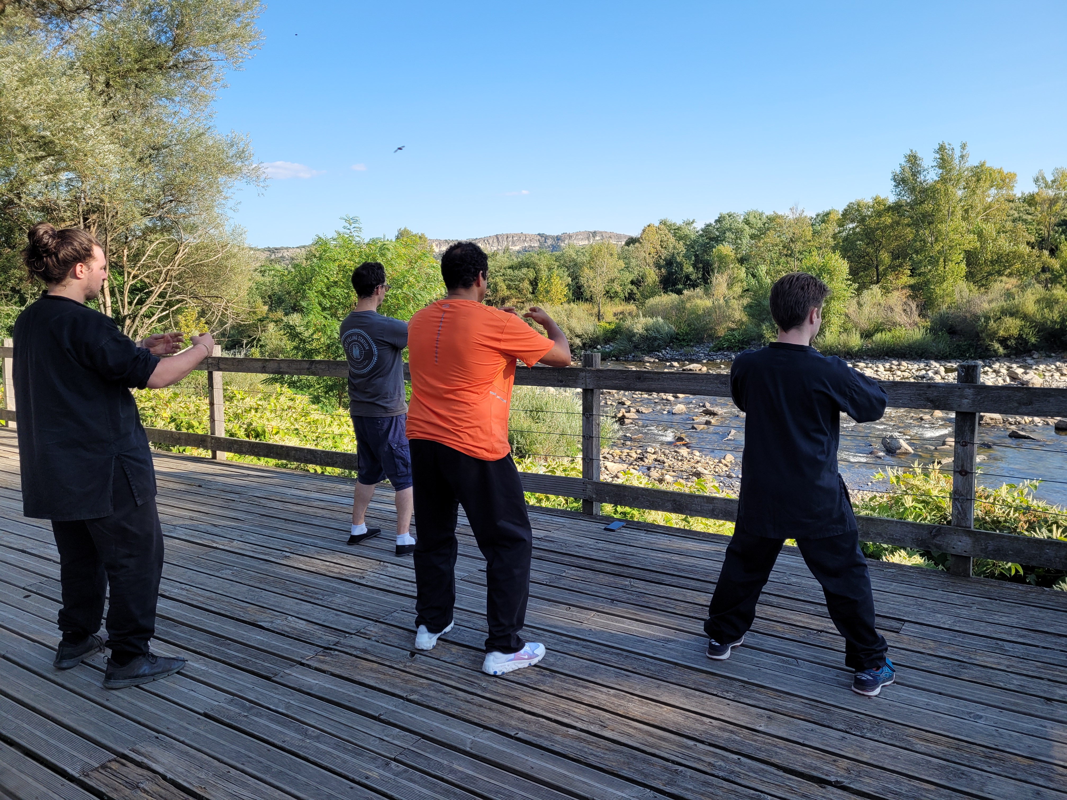 Groupe de pratiquants face à la rivière lors d'une séance en extérieur en Ardèche